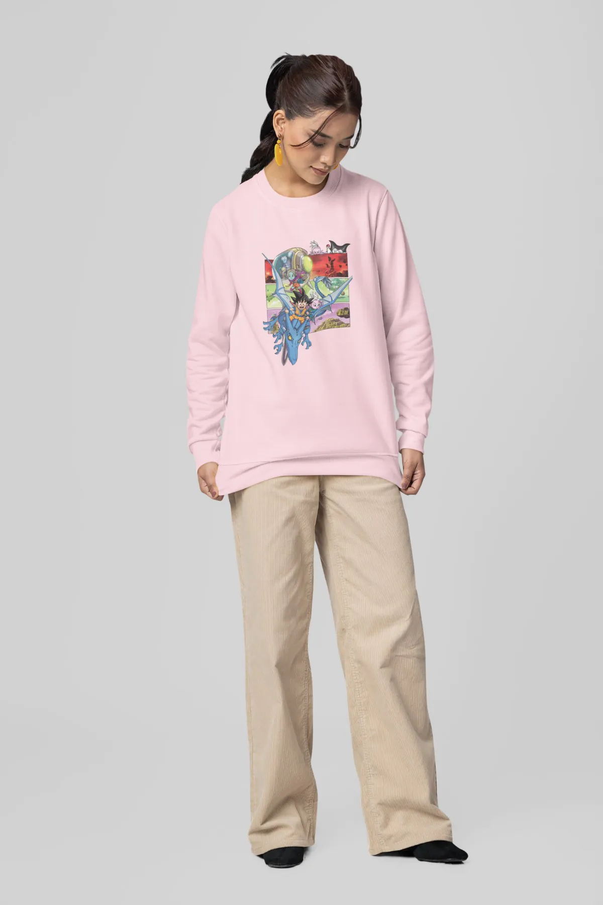 Woman wearing a baby pink sweatshirt with Dragon Ball Daima design.